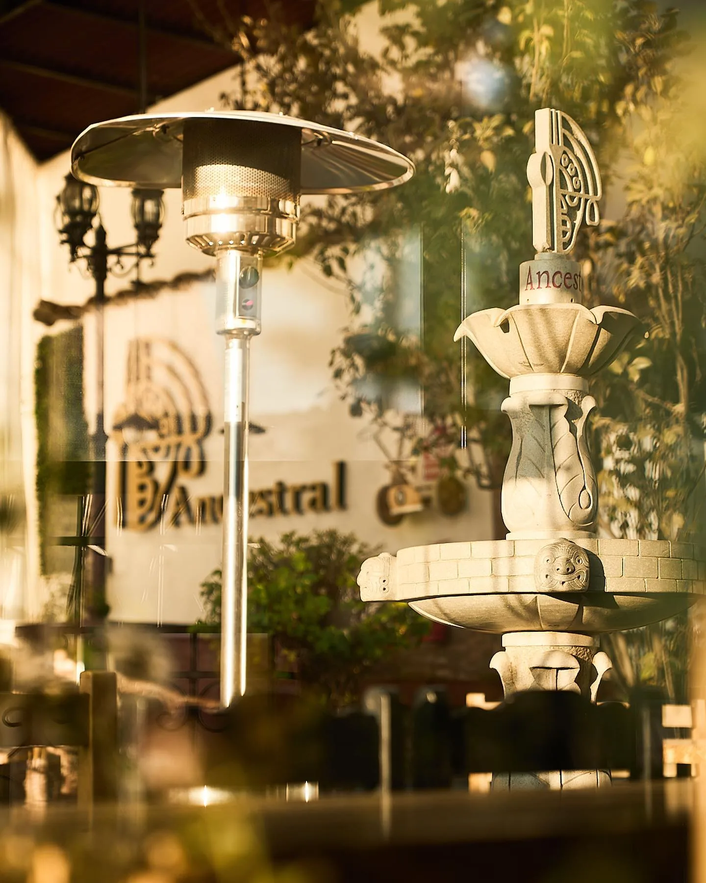 Ancestral's courtyard at sunset, with the stone fountain and the restaurant sign